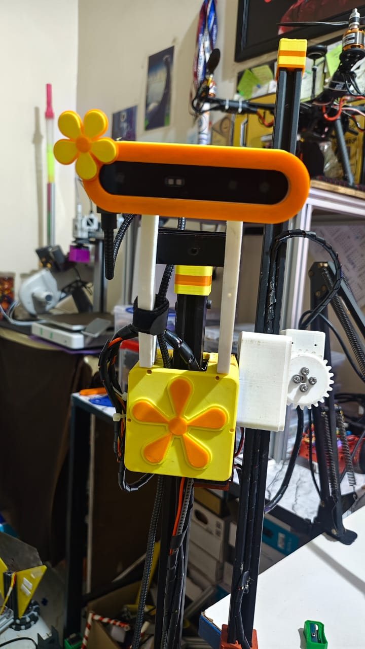 Front view of the camera rig: an orange depth-camera housing with a yellow flower, above a yellow control box with an orange flower